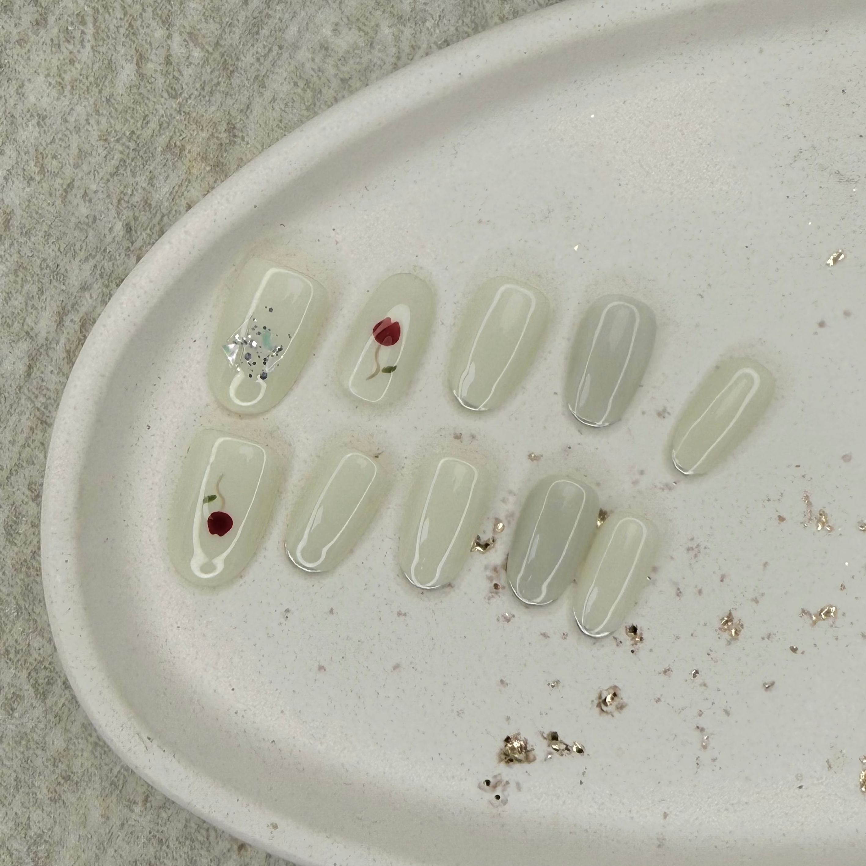 Clear press on nail polish samples on a beige tray with a textured background
