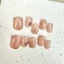 Close-up of blush nude pink press-on nails with small floral accents and gold marble lines, handcrafted for weddings and elegant occasions.