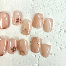 Close-up of blush nude pink press-on nails with small floral accents and gold marble lines, handcrafted for weddings and elegant occasions.