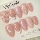 Close-up of nude press-on nails with 3D white floral design, gold outline, and soft marble accents, handcrafted for weddings and elegant events.