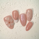 Close-up of nude press-on nails with 3D white floral design, gold outline, and soft marble accents, handcrafted for weddings and elegant events.