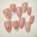 Close-up of nude press-on nails with 3D white floral design, gold outline, and soft marble accents, handcrafted for weddings and elegant events.