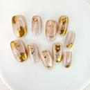 Handcrafted nude and silver press-on nails with 3D gold glitter flower design and metallic shimmer – made by Vlei Nails Cape Town.
