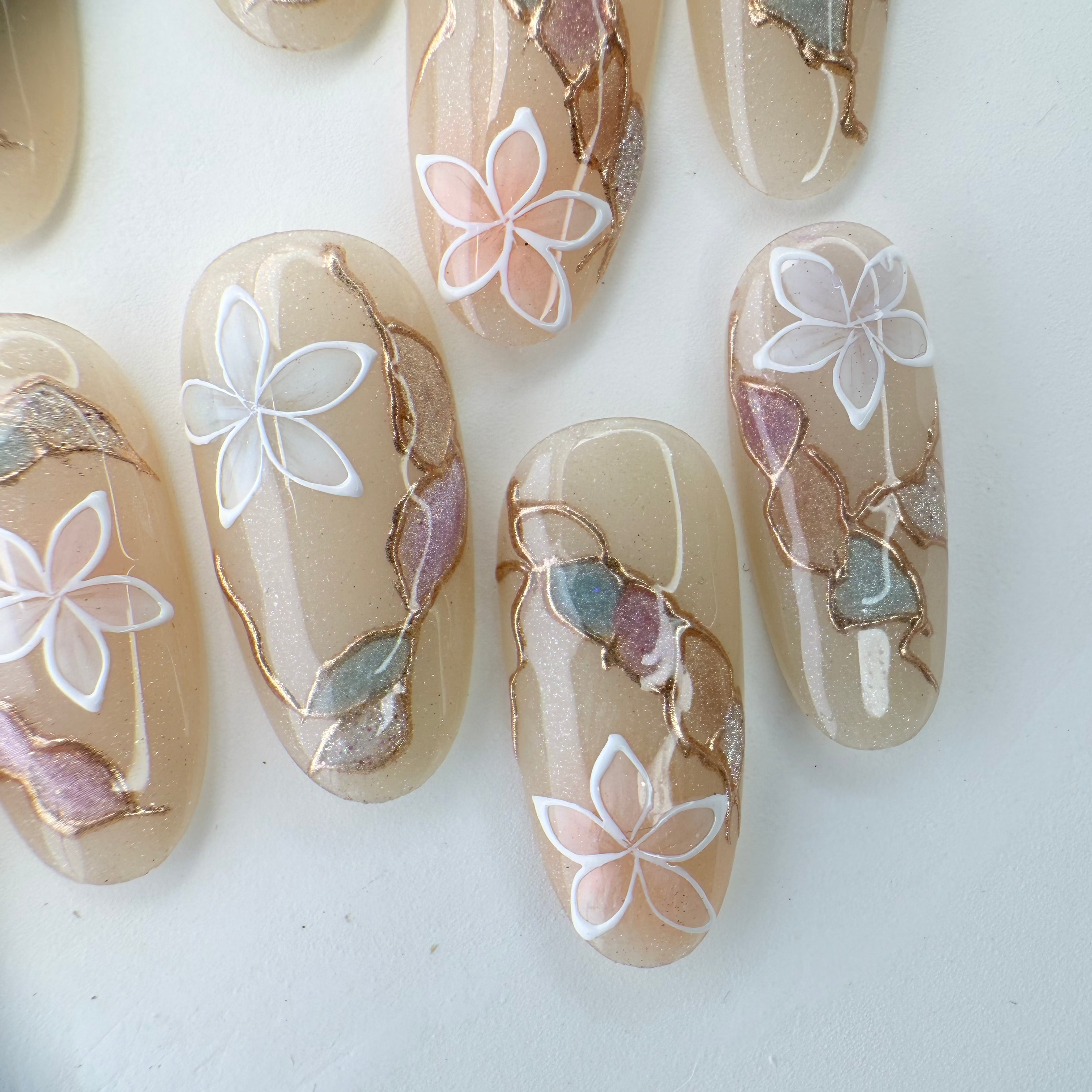 Handcrafted blush nude press-on nails with pearl flowers and gold shimmer lines – made by Vlei Nails Cape Town.
