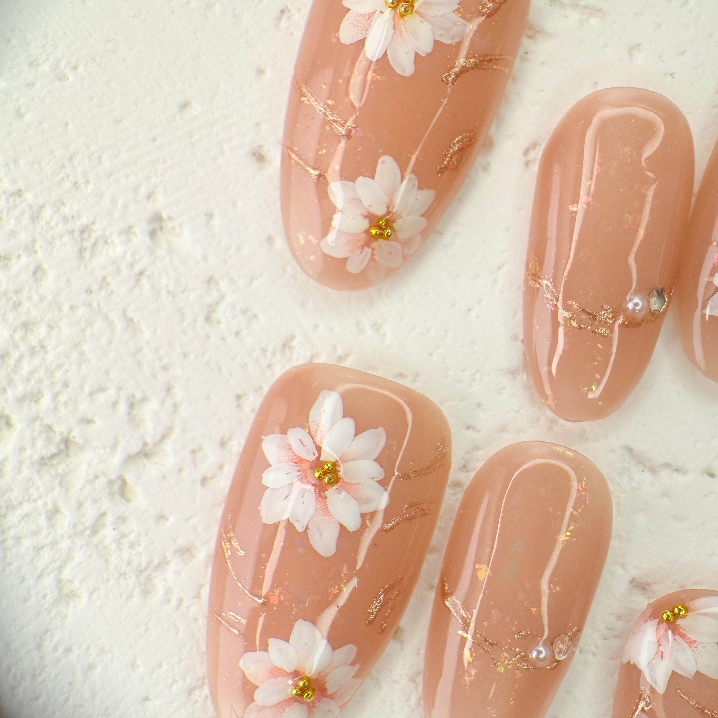 Handcrafted nude pink press-on nails with 3D pearl flowers and gold foil shimmer – made by Vlei Nails Cape Town.
