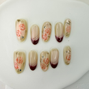 Handcrafted nude press-on nails with red French tips and 3D pink rose accents – made by Vlei Nails Cape Town.
