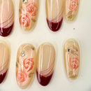Handcrafted nude press-on nails with red French tips and 3D pink rose accents – made by Vlei Nails Cape Town.
