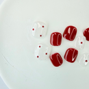 Red and white kiddies press-on nails with glossy finish and tiny polka dot accents on a white background.