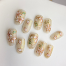 Frosty  press-on nails with white 3D flowers, gold lines and marble accents.
