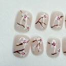 Cherry blossom floral press-on nails on milky nude base, short round.