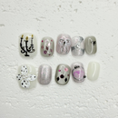 Grey press-on nails with bow design, silver shimmer gel, crystal embellishments, pearl flower accent and artistic candle nail art