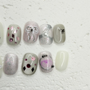Grey press-on nails with bow design, silver shimmer gel, crystal embellishments, pearl flower accent and artistic candle nail art